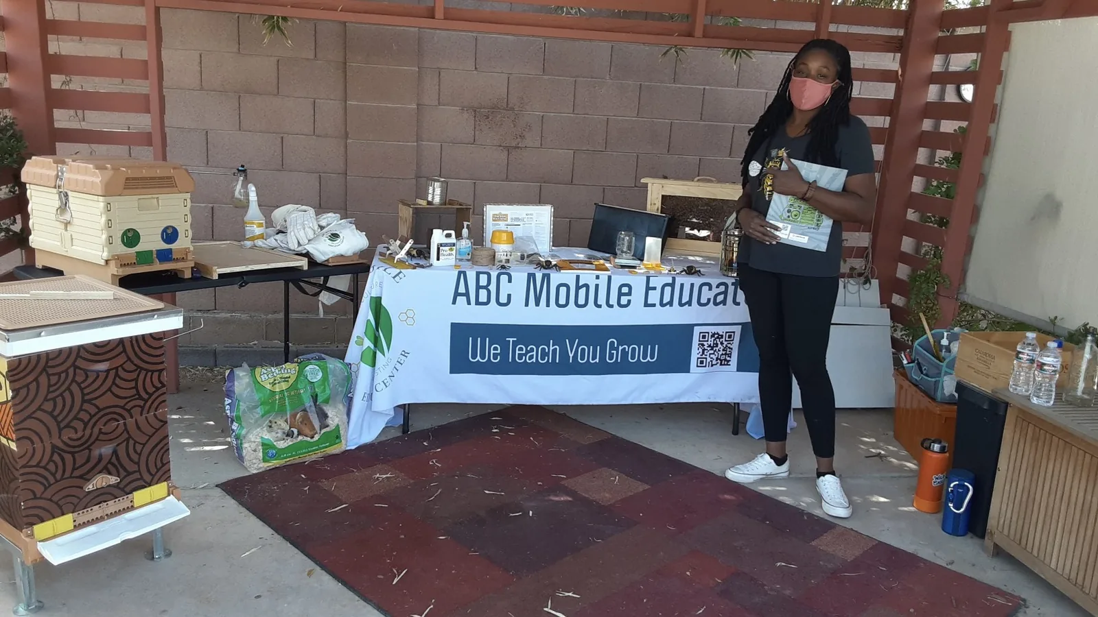 Nika Forte' at an ABC Mobile Education Center table with beekeeping equipment and a banner reading We Teach You Grow